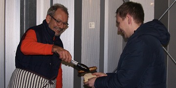 Weihnachtsfeier 2017: Wurstausgabe Herr Kampmann reicht unserem Schüler eine Wurst